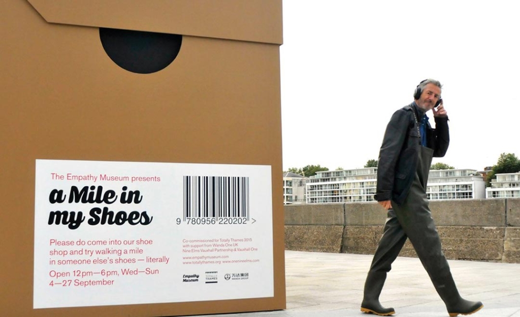 A man walking with headphones on next to a giant shoe box