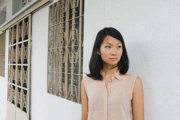 Inez Tan stands outside by a white wall