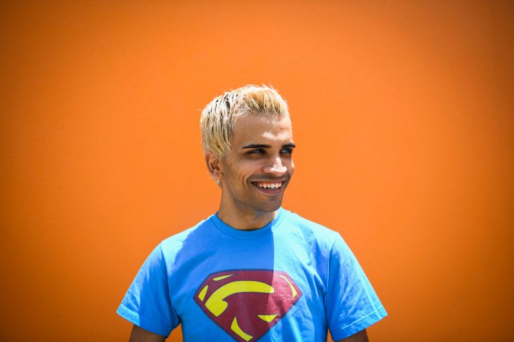 A bright portrait of Raphael Farmer. He is wearing a superman t-shirt and smiling. 