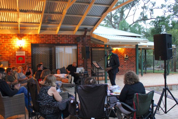 Photo of Colin Archibald sharing his story to a group of people in a backyard