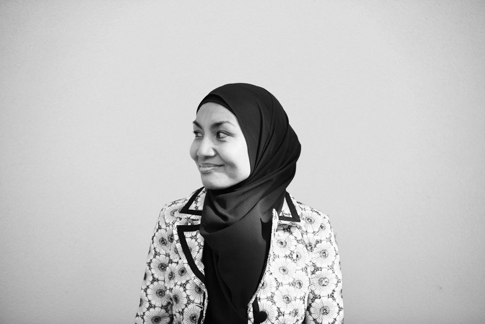 A black and white image of Raihanaty looking away from the camera and smiling.