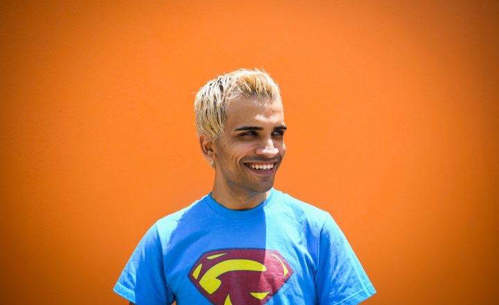 A bright portrait of Raphael Farmer. He is wearing a superman t-shirt and smiling.