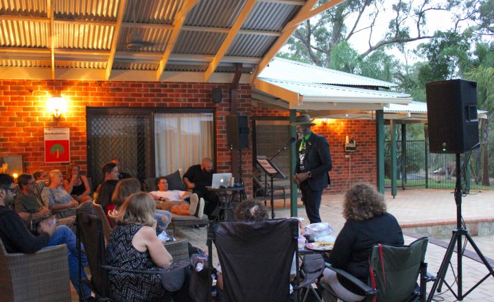 Photo of Colin Archibald sharing his story to a group of people in a backyard