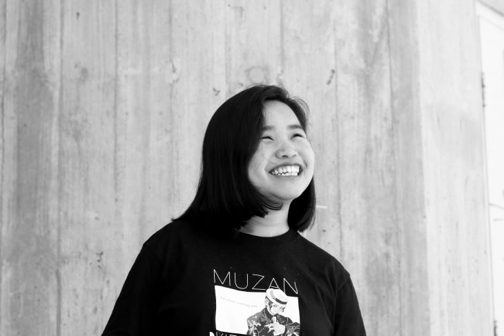 A black and white portrait of Simeon Neo. She is looking up at the sky and smiling.