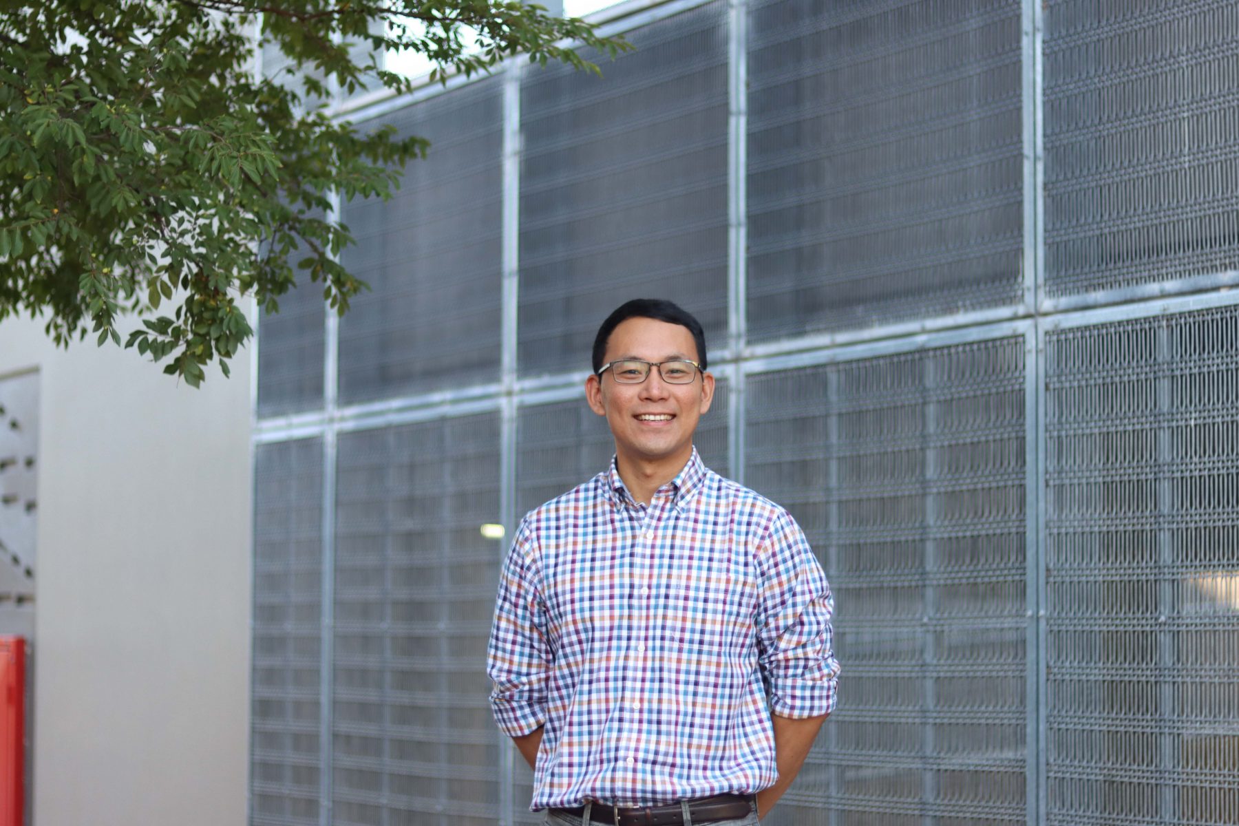 Photo of Chris Lin standing in front of a grated metal wall
